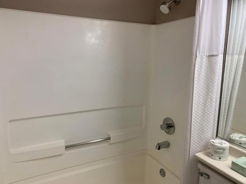 a white bathroom with a shower and a sink at Super 8 by Wyndham Greeley in Greeley