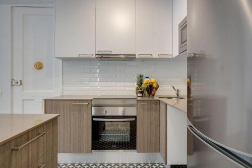 cocina con armarios blancos y fogones en LucasLand Apartments Barcelona, en Barcelona