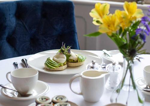 a table with a plate of food and cups and flowers at Kilkea Castle in Kilkea