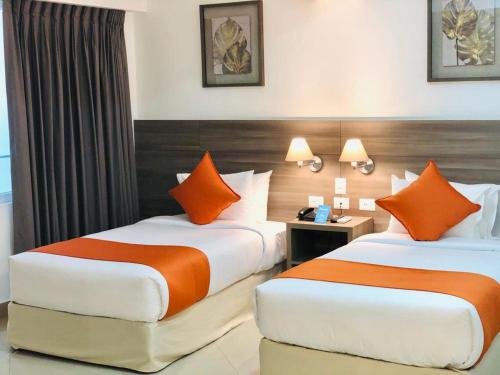 two beds in a hotel room with orange pillows at Howard Johnson by Wyndham Lima Miraflores Art House in Lima