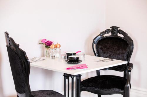 einen Tisch mit zwei schwarzen Stühlen und einen weißen Tisch mit Blumen in der Unterkunft The Rosewood Torquay in Torquay