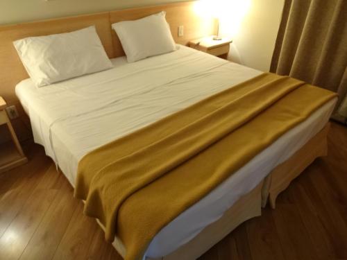 a bedroom with a large bed with white sheets and pillows at Residencial Bella Vista Suites in Sao Paulo