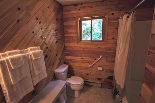 baño con paredes de madera, aseo y ventana en High Falls Bay Cottages, Camping & Waterpark, en Bracebridge