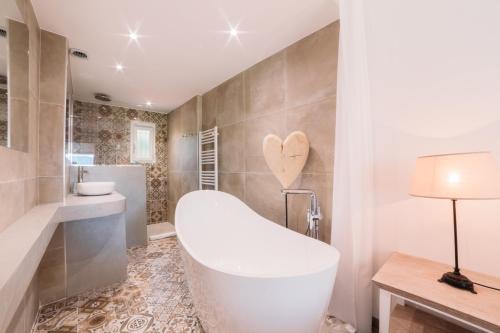 a bathroom with a white tub and a sink at Hôtel Font Mourier in Cogolin