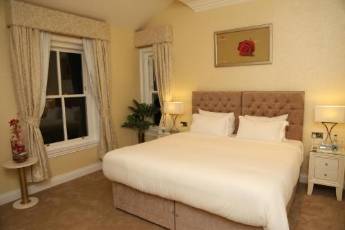a bedroom with a large white bed with two windows at The Old Hall Hotel in Coventry