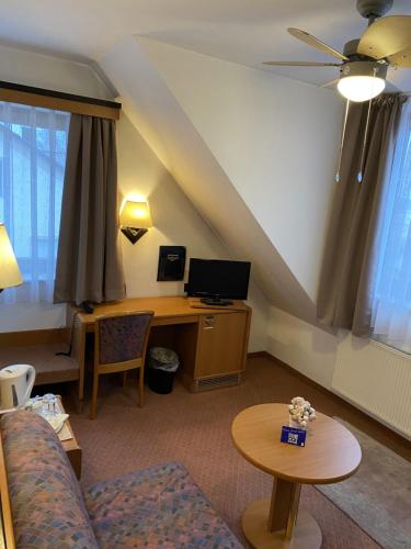 a living room with a couch and a desk with a computer at Hotel Seebach in Großenseebach