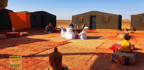 a group of people sitting in front of tents in the desert at Kasbah Les Alizes Du Desert in Mhamid