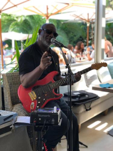 a man sitting in a chair playing a guitar at Hôtel Font Mourier in Cogolin