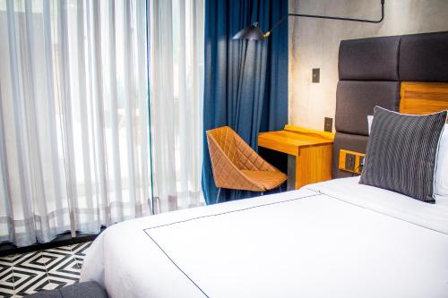a hotel room with a bed and a chair at Diez Diez Collection in Mérida