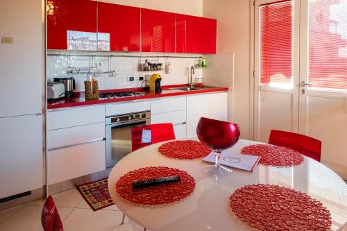 a kitchen with red cabinets and a table with a wine glass at casa di alessio a 200 metri dal mare in Acireale