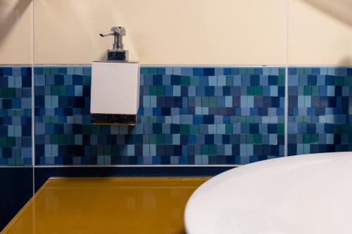a bathroom with a toilet and a tile wall at casa di alessio a 200 metri dal mare in Acireale
