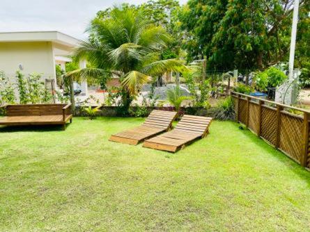 a backyard with two benches on the grass at CHALES VILLAGE COR-PENINSULA DE MARAU-BAHIA in Barra Grande