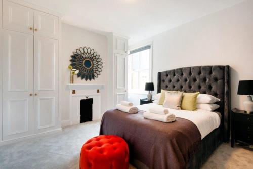 a bedroom with a large bed with a red ottoman at Modern Family Home in London Close to Amenities and Train in London