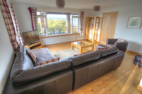 a living room with a leather couch and a table at ArdFyne on Lochfyne in Strachur