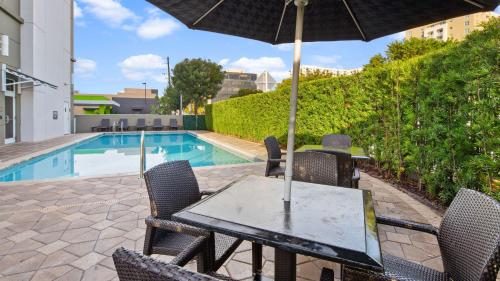 a table with an umbrella next to a swimming pool at Best Western Plus Miami Intl Airport Hotel & Suites Coral Gables in Miami