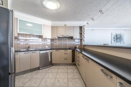 a kitchen with stainless steel appliances and white cabinets at Biarritz Apartments in Gold Coast