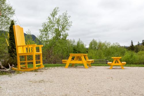 tres sillas amarillas y una mesa de picnic en un parque en Middle Brook Cottages & Chalets en Glenburnie