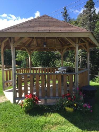 a wooden gazebo in a yard with flowers at Middle Brook Cottages & Chalets in Glenburnie