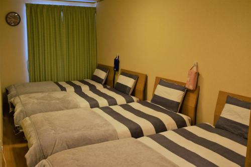 three beds in a room with green curtains at Hidamari in Takayama