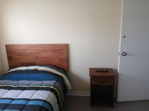 1 dormitorio con 1 cama con cabecero de madera y mesa en Hospedaje casa Arrayan, en La Serena