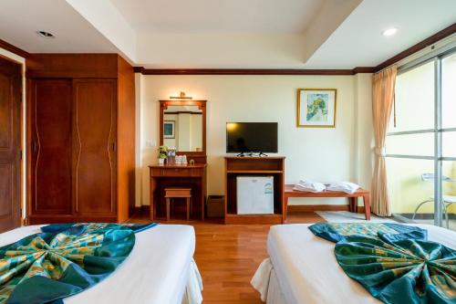 a bedroom with two beds and a desk and a television at Chomsin Hua Hin ชมสินธุ์ หัวหิน in Hua Hin