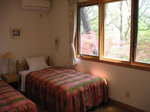 a bedroom with a bed and a window at B&Bペンション Second House Plus in Nikko