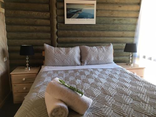 a bedroom with a bed with a stuffed animal on it at Lazy Acre Log Cabins in Lakes Entrance