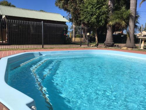 a swimming pool with blue water in front of a fence at Lazy Acre Log Cabins in Lakes Entrance