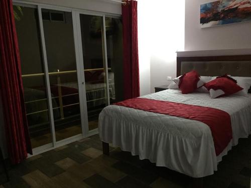 a bedroom with a bed with red sheets and a window at Casa Gaviota Dorada in Baños