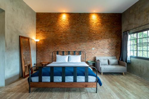 a bedroom with a bed and a brick wall at The Barn Hua Hin in Khao Tao
