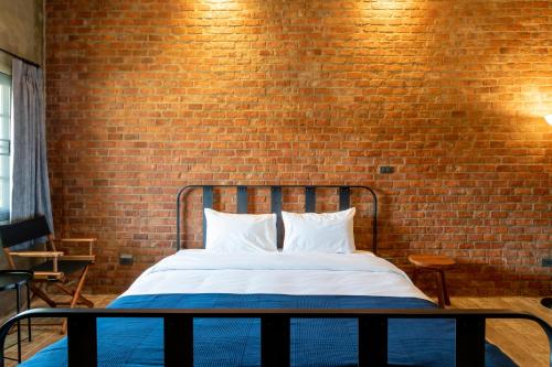 a bedroom with a bed with a brick wall at The Barn Hua Hin in Khao Tao