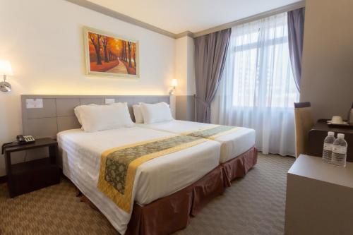 a hotel room with a large bed and a window at Hallmark Leisure Hotel in Melaka
