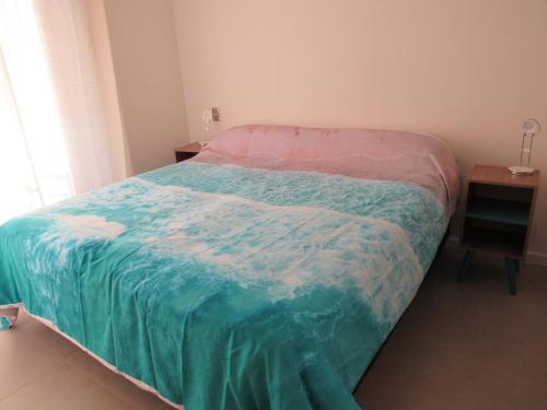 ein Bett mit einer grünen und rosa Decke drauf in der Unterkunft Birdhouse Apartment in Santiago