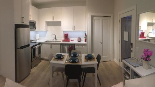 a kitchen with a table and a small kitchen with white cabinets at Mollys Cottage-The Suite on Vancouver Island near YYJ Airport and the WA and BC Ferries in North Saanich
