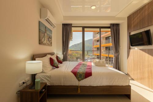 a bedroom with a bed and a large window at NaiHarn Sea Condo by Holy Cow, 1-BR, mountain view in Nai Harn Beach