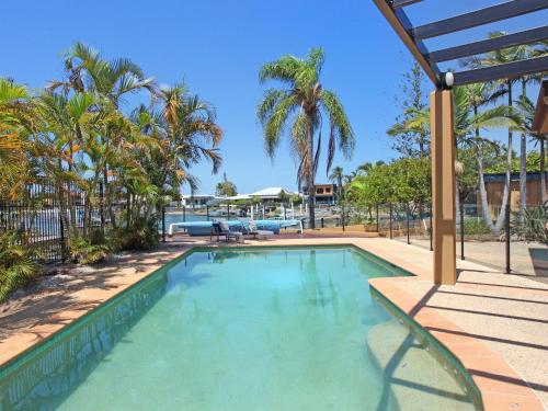 a swimming pool with palm trees in the background at Tarcoola 41 in Mooloolaba