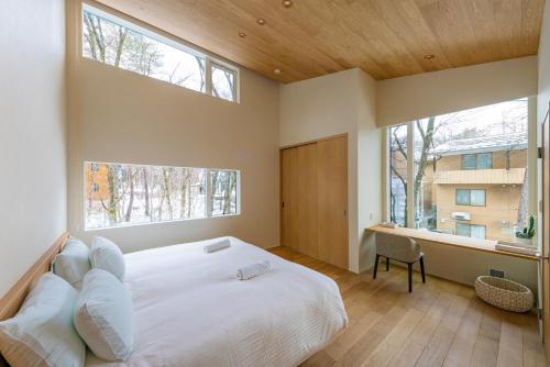 1 dormitorio con 1 cama blanca grande y 2 ventanas en Kairos by the Mountain by The Hakuba Collection en Hakuba