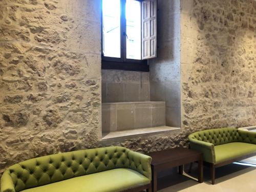 a living room with two green couches and a window at Hospedería Monasterio de La Vid in La Vid y Barrios