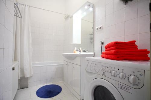Mozart Apartments - Rögergasse في فيينا: حمام مع غسالة ملابس ومناشف حمراء