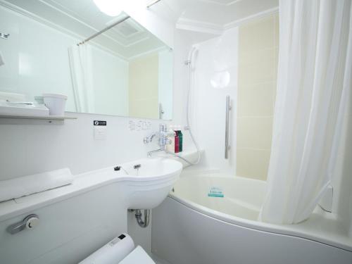 Baño blanco con bañera, lavabo y espejo en APA Hotel Hitachinaka Katsuta Station en Hitachinaka