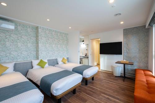 a hotel room with two beds and a flat screen tv at Hotel SAILS Asakusa in Tokyo