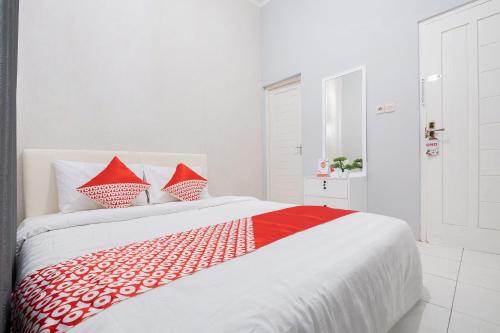 a white and red bed with red pillows on it at Super OYO 2727 Nareswari Guest House Syariah in Magelang