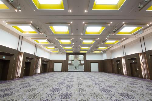 an empty ballroom with a large room with lights on the ceiling at ANA Crowne Plaza Yonago by IHG in Yonago