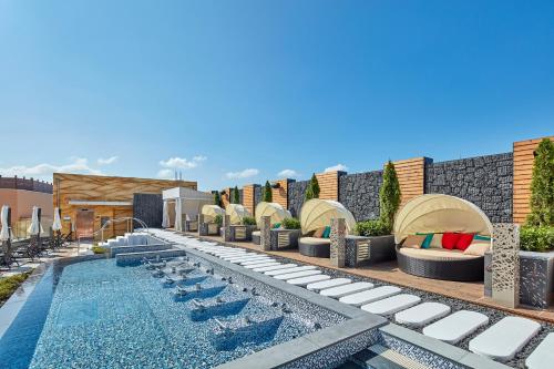 a pool with chaise lounges and chairs next to a building at Shinhwa Jeju Shinhwa World Hotels in Seogwipo