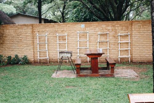 a wooden bench and a table in front of a brick wall at Bosveldrus Gastehuis in Vaalwater