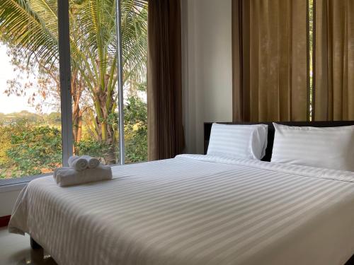 Ένα ή περισσότερα κρεβάτια σε δωμάτιο στο ร่มปาล์มรีสอร์ท สระบุรี Rompalm Saraburi