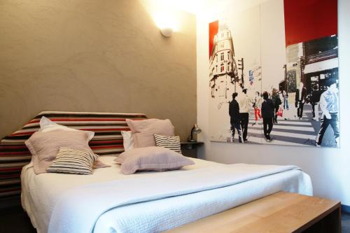 - un lit dans une chambre avec une photo sur le mur dans l'établissement Hôtel et Restaurant Le Regina, au Puy-en-Velay