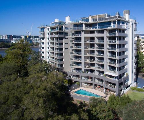 a large white apartment building with a swimming pool at Inn on the Park Apartments in Brisbane