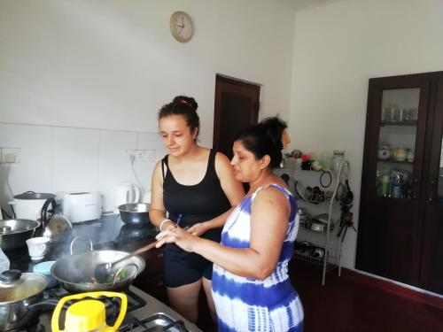 two women standing in a kitchen preparing food at Mahaweli Shades in Kandy