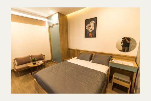a hotel room with a bed and a chair at AHA Thang Bom Apartment Da Nang in Danang